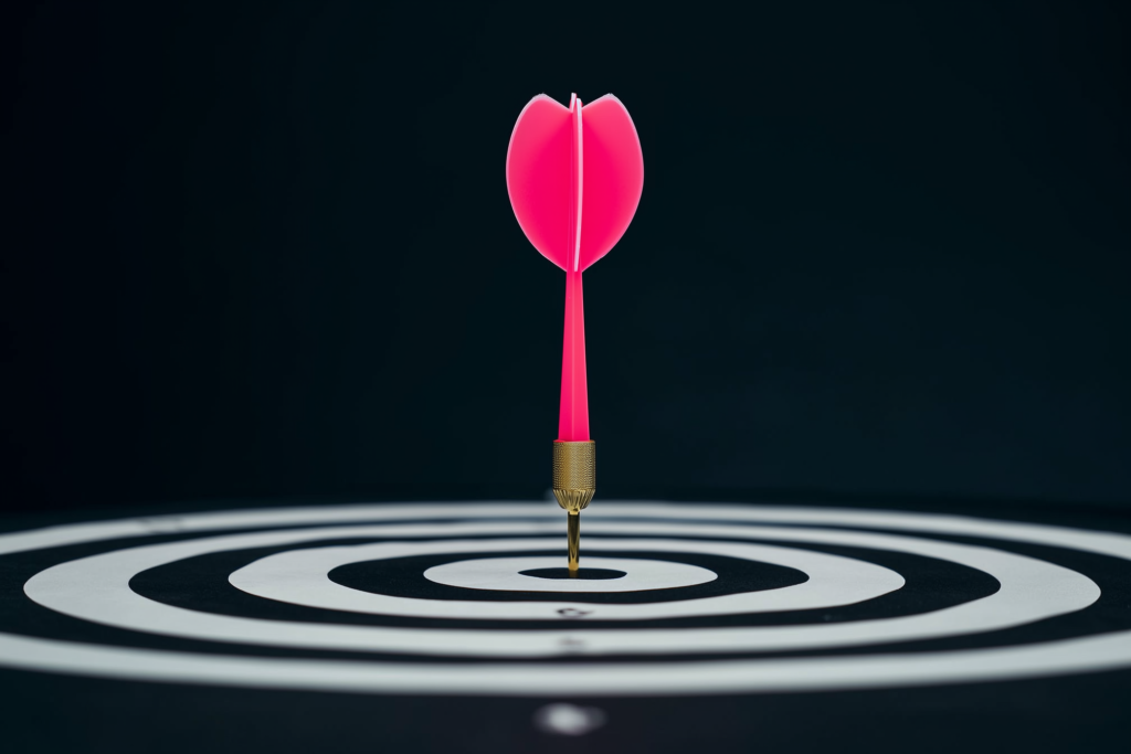 A coral dart of light hitting a bullseye on a dark surface.