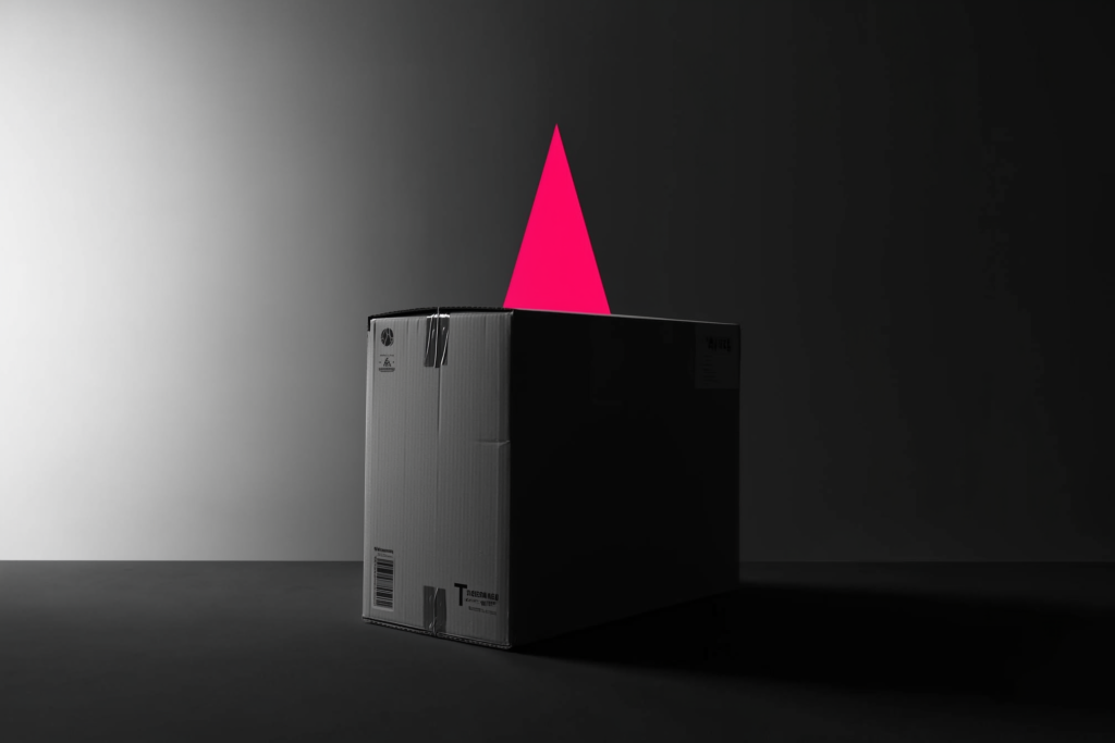 A shipping carton on a dark surface with a rising coral trend line of light.