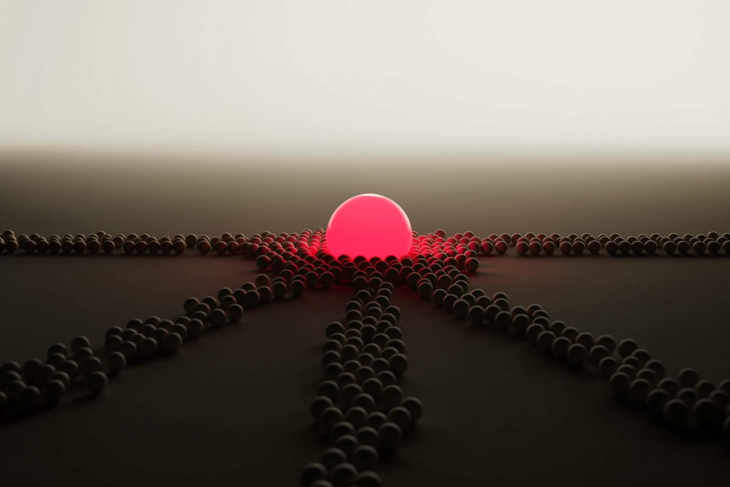 Small spheres clustering around one glowing coral sphere on a dark surface.