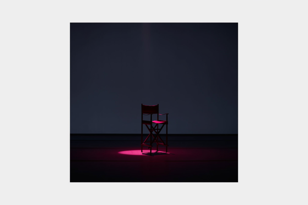 A spotlight with a coral beam on a dark stage.