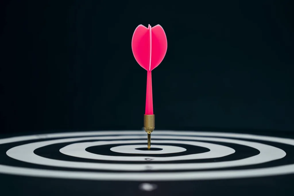 A coral dart of light hitting a bullseye on a dark surface.