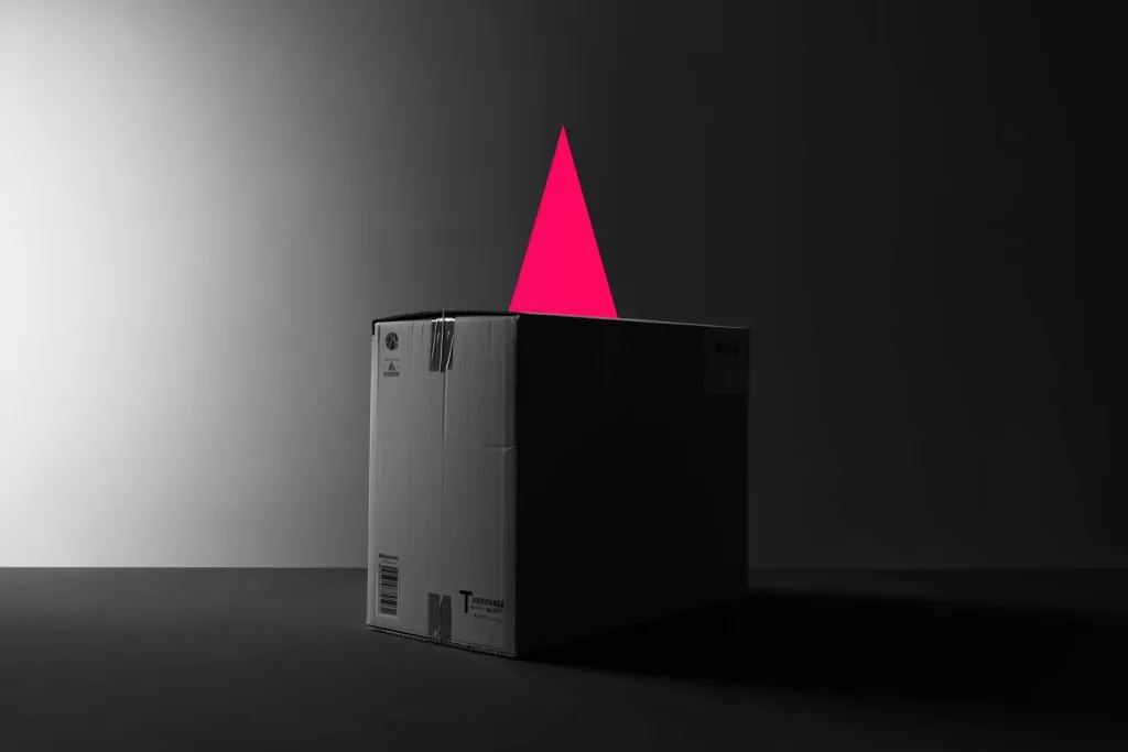 A shipping carton on a dark surface with a rising coral trend line of light.
