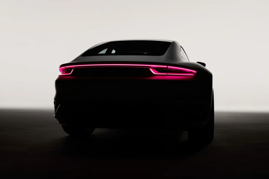 A car silhouette on a dark surface with a coral rim light along its edge.