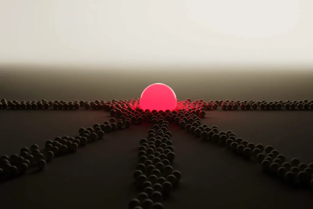 Small spheres clustering around one glowing coral sphere on a dark surface.