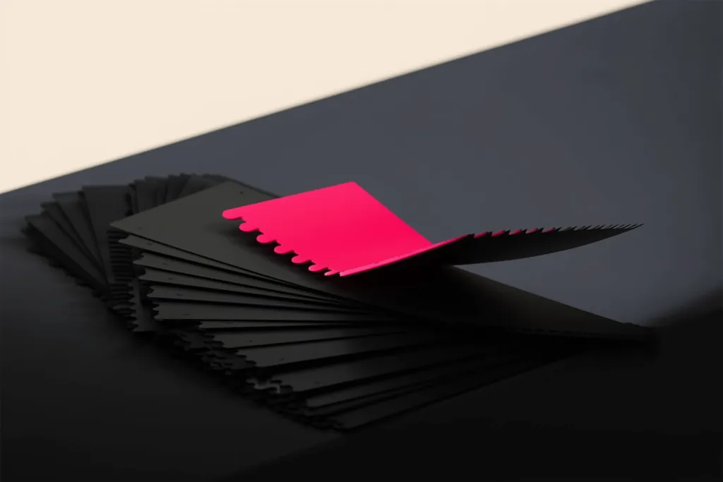 Paint swatches on a dark surface with one coral swatch in focus.