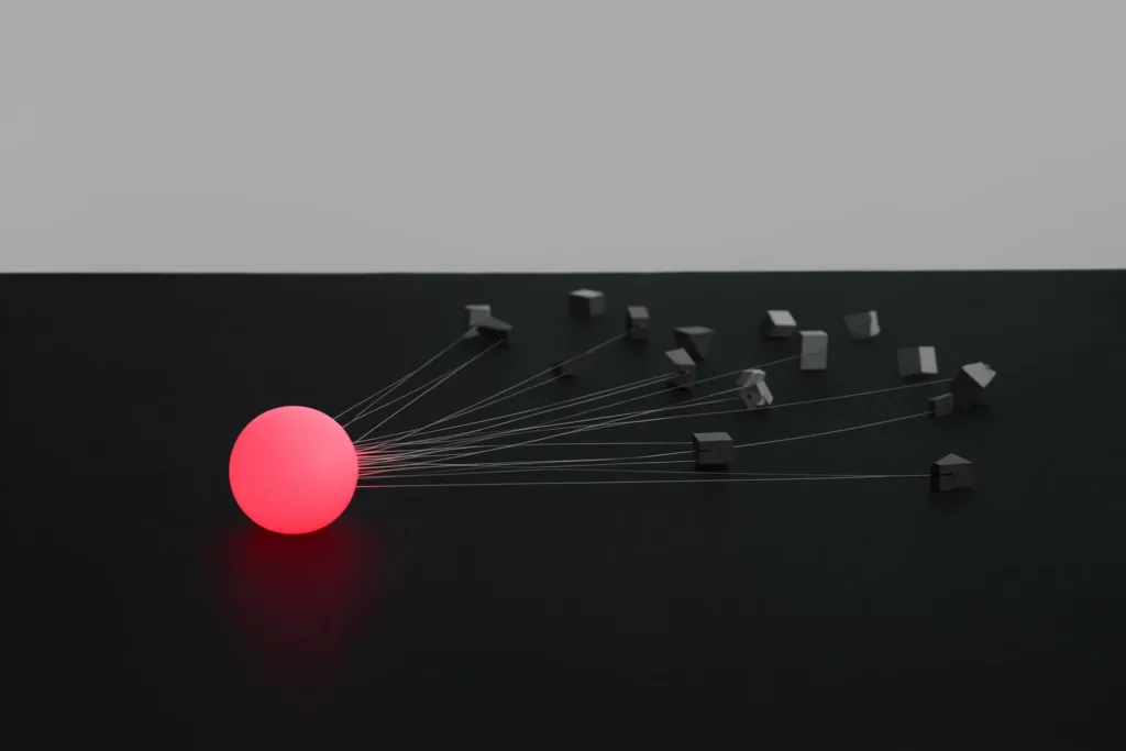 One glowing coral sphere branching into many shapes on a dark surface.