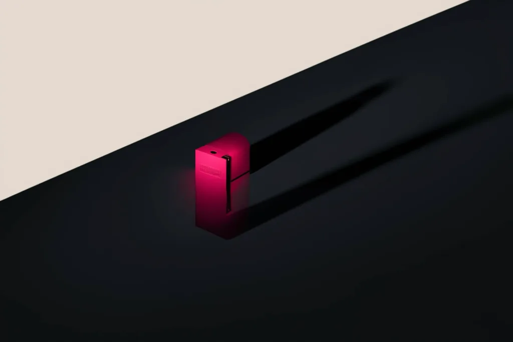 A premium product casting a long shadow, one edge lit coral, on a dark surface.