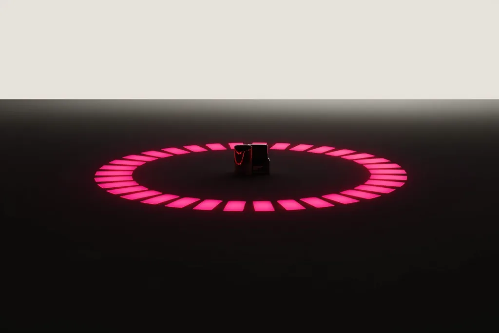 A coral loop of light circling a product silhouette on a dark surface.