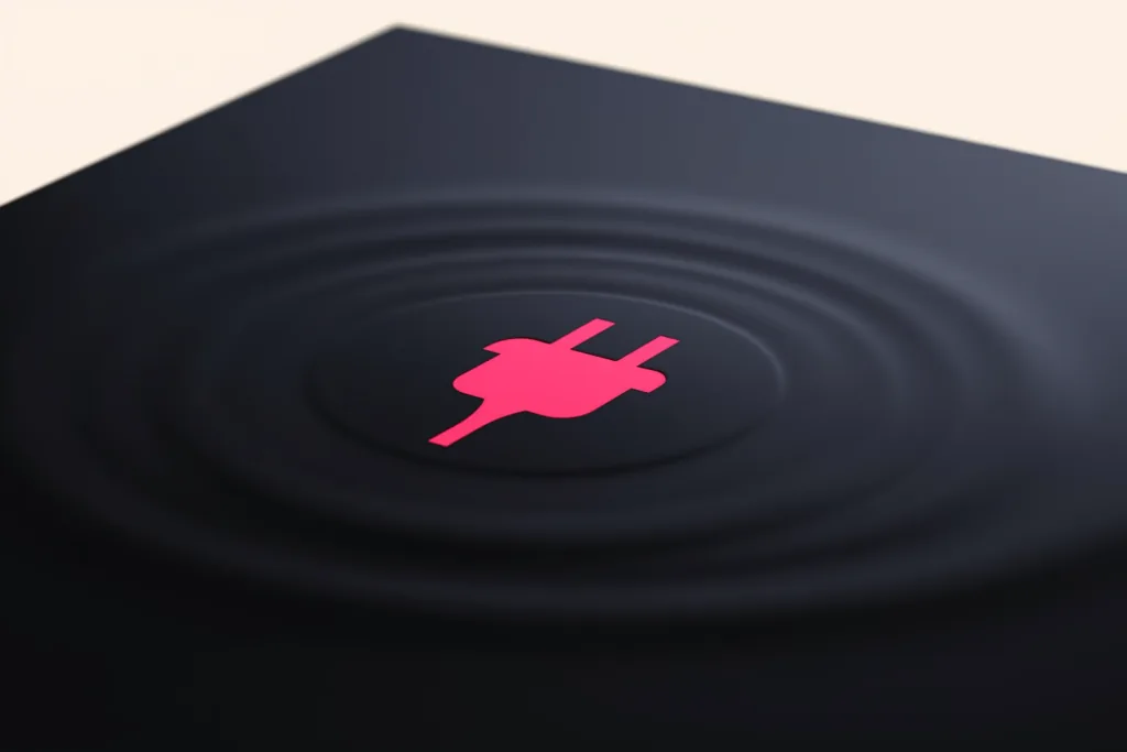 A coral charging-plug of light on a dark surface.