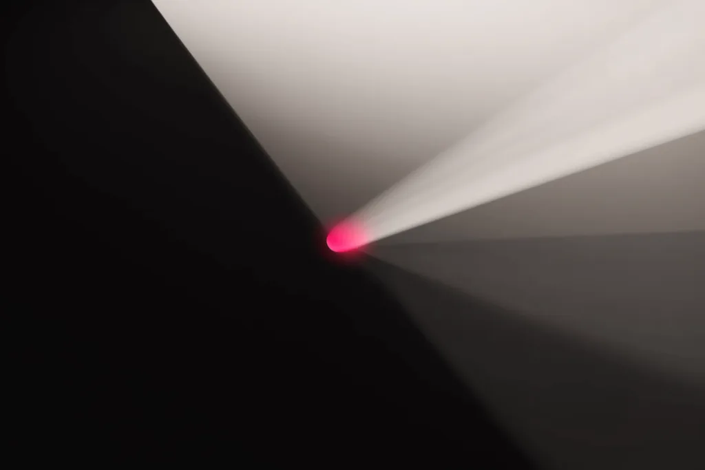 A coral beam fanning into many channels on a dark surface.
