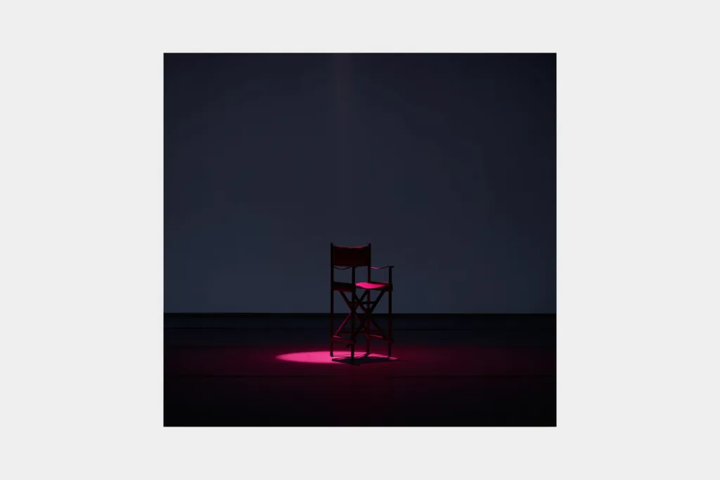 A spotlight with a coral beam on a dark stage.