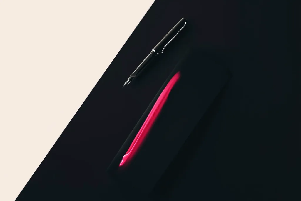 A fountain pen and a sealed document with a coral-glowing seal on a dark surface.