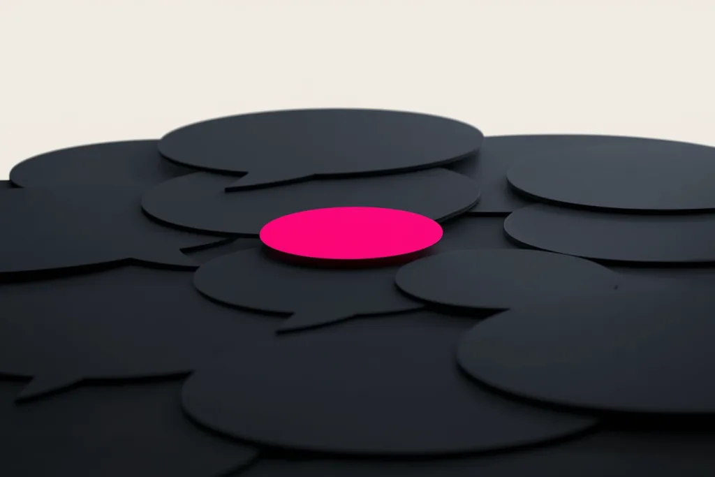 Speech bubbles on a dark surface with one glowing coral bubble rising.