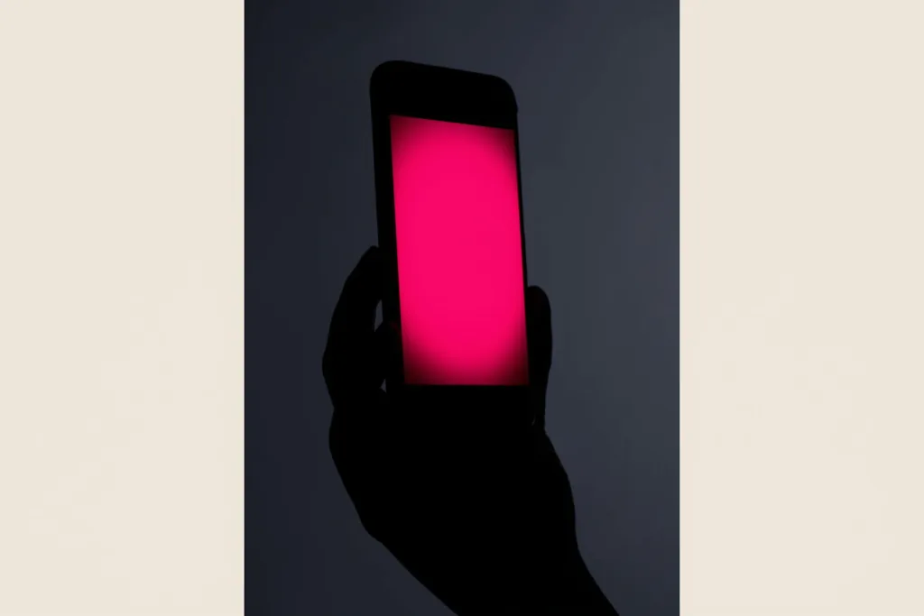 A phone glowing with a coral speech-bubble of light against a dark background.