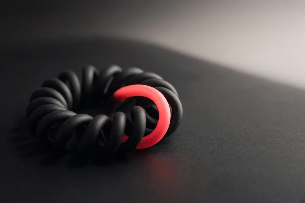 A coiled telephone cord with one coil glowing coral pink.