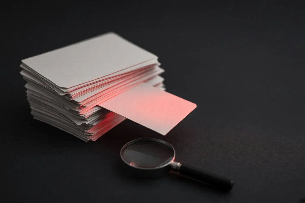 A stack of index cards with one card pulled out and lit in coral pink.