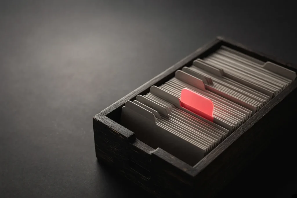 An index drawer of card dividers with one tab glowing coral pink.
